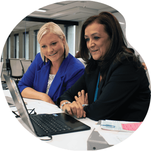two instructional coaches looking intently at a laptop in a boardroom setting
